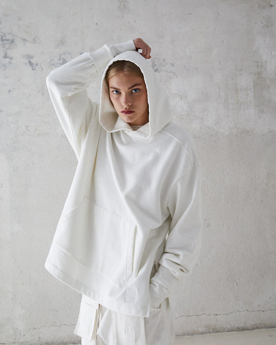 Female model wearing a white hoodie with the hood up